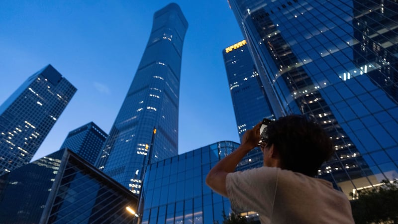 A passerby tries to take photo of the damage on the Citic Tower also known as Zun Tower in...